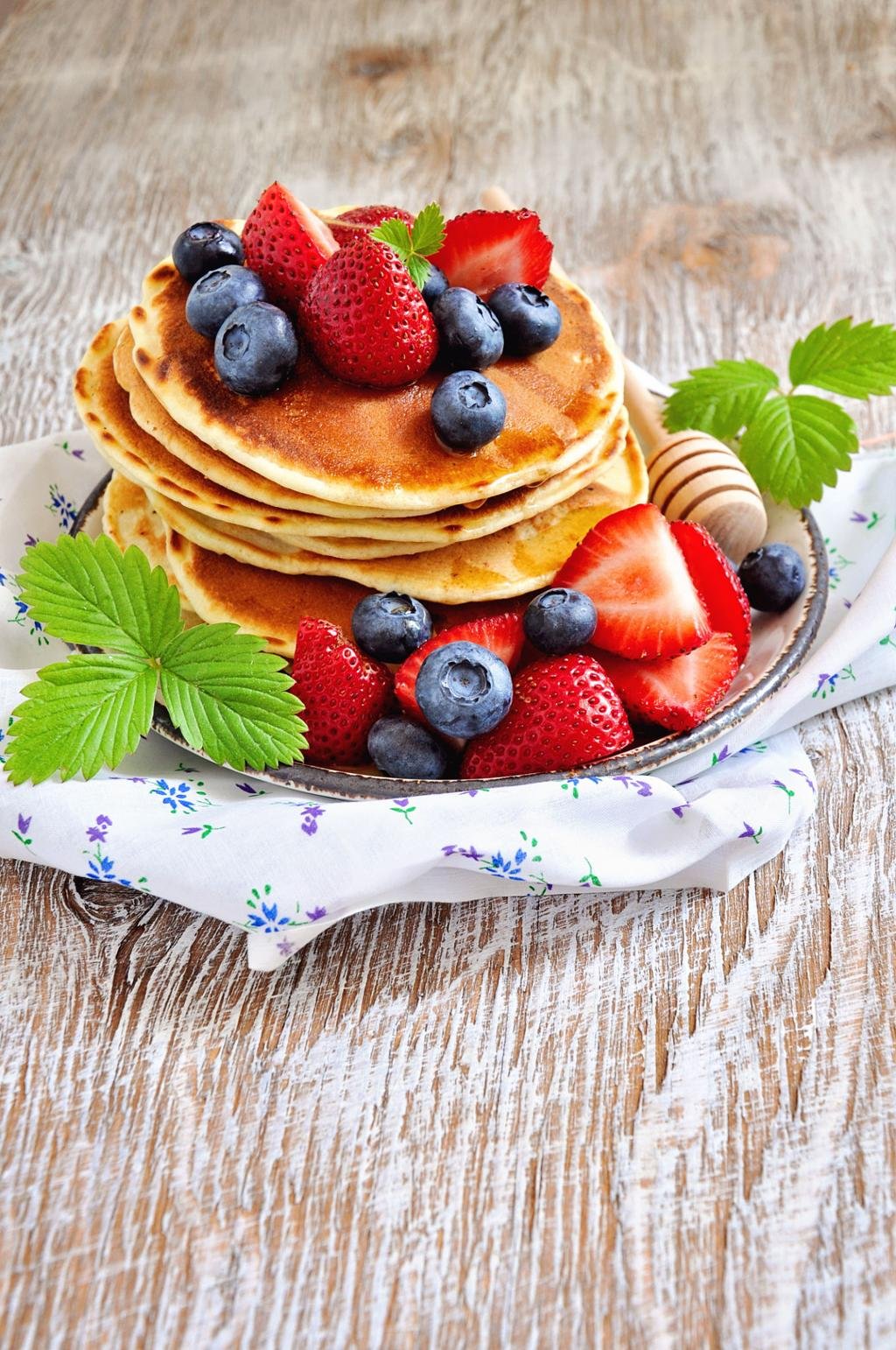 Fluffy pancakes stacked with syrup, butter, and fresh fruits